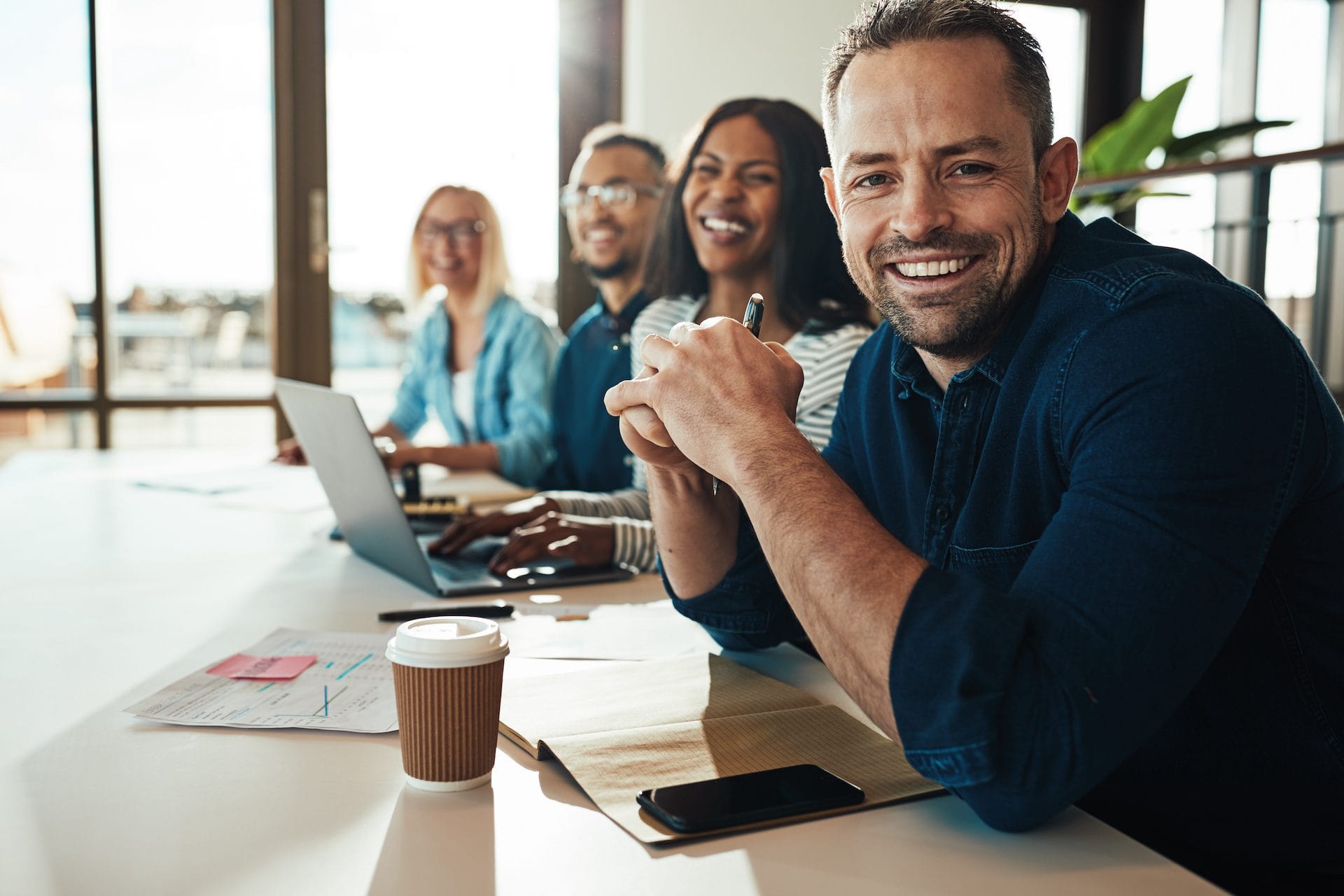 Smiling mature businessman sitting with colleagues in an office