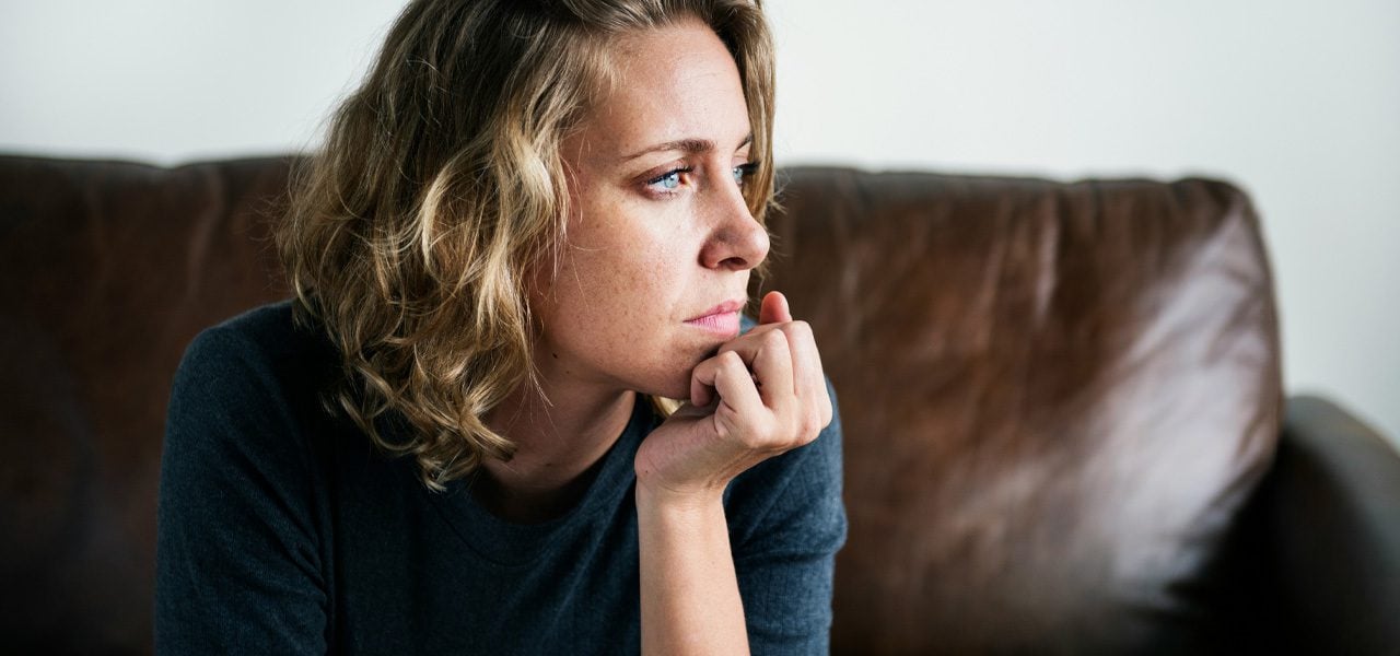 Woman looking thoughtfully to the left with her hand on her chin